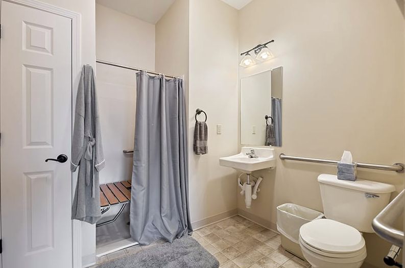 Modern bathroom with shower, sink, and toilet, featuring gray accents.