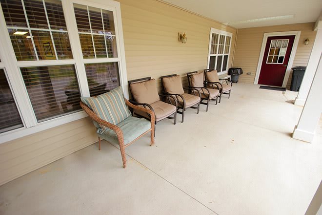 A row of chairs on a spacious porch, perfect for relaxing outdoors.