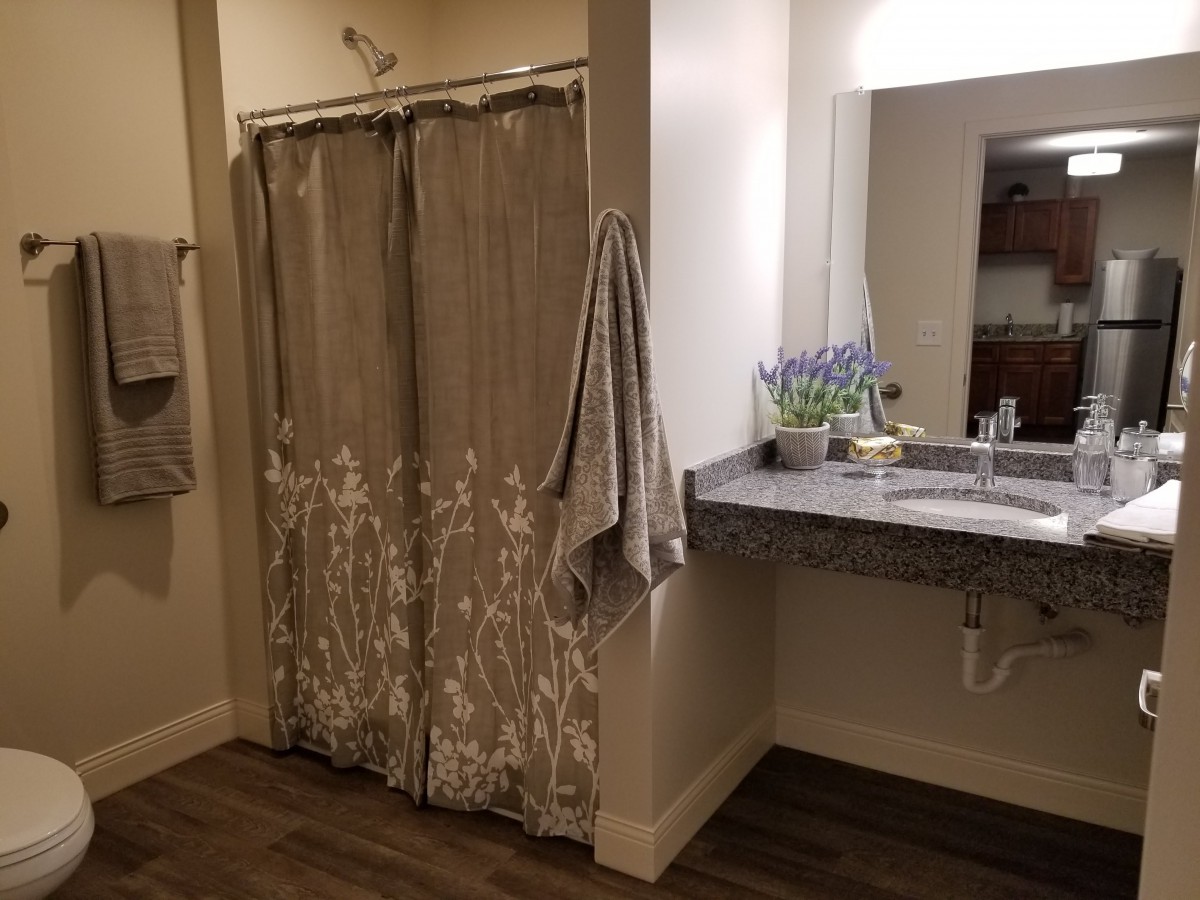 A cozy bathroom featuring a floral shower curtain, a sink with a mirror, and decorative touches like a potted plant.