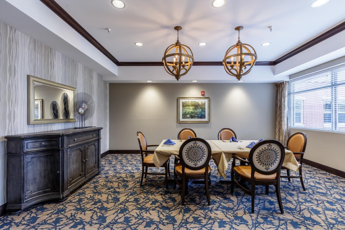 An elegant dining room with a table and chairs, decorated with chandeliers and artwork.