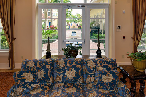 A beautifully decorated lobby area featuring a floral patterned sofa, with a view of the lush outdoor landscape through the glass doors.