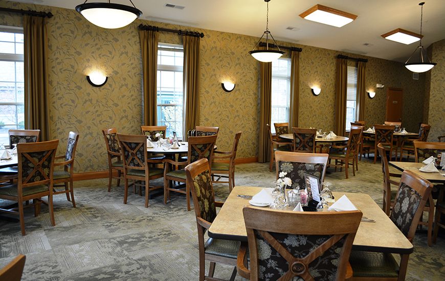 A cozy restaurant dining area with neatly arranged tables and chairs, complemented by warm lighting.