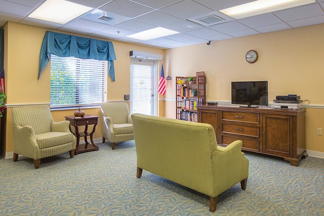 A cozy living room with comfortable seating, a TV, and a bookshelf.