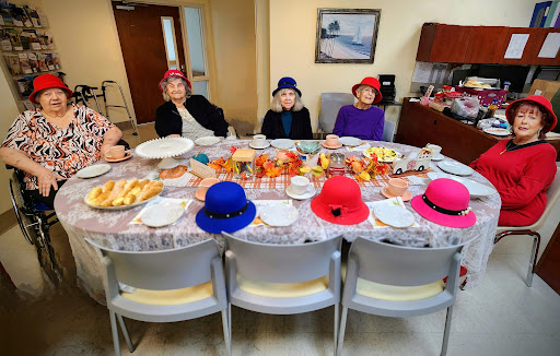 A cheerful gathering of seniors enjoying a meal with colorful hats on display.