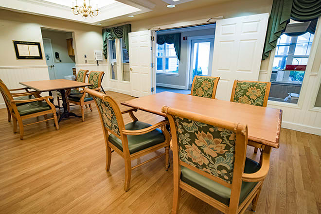 A cozy dining room with wooden tables and upholstered chairs, featuring a warm interior design.
