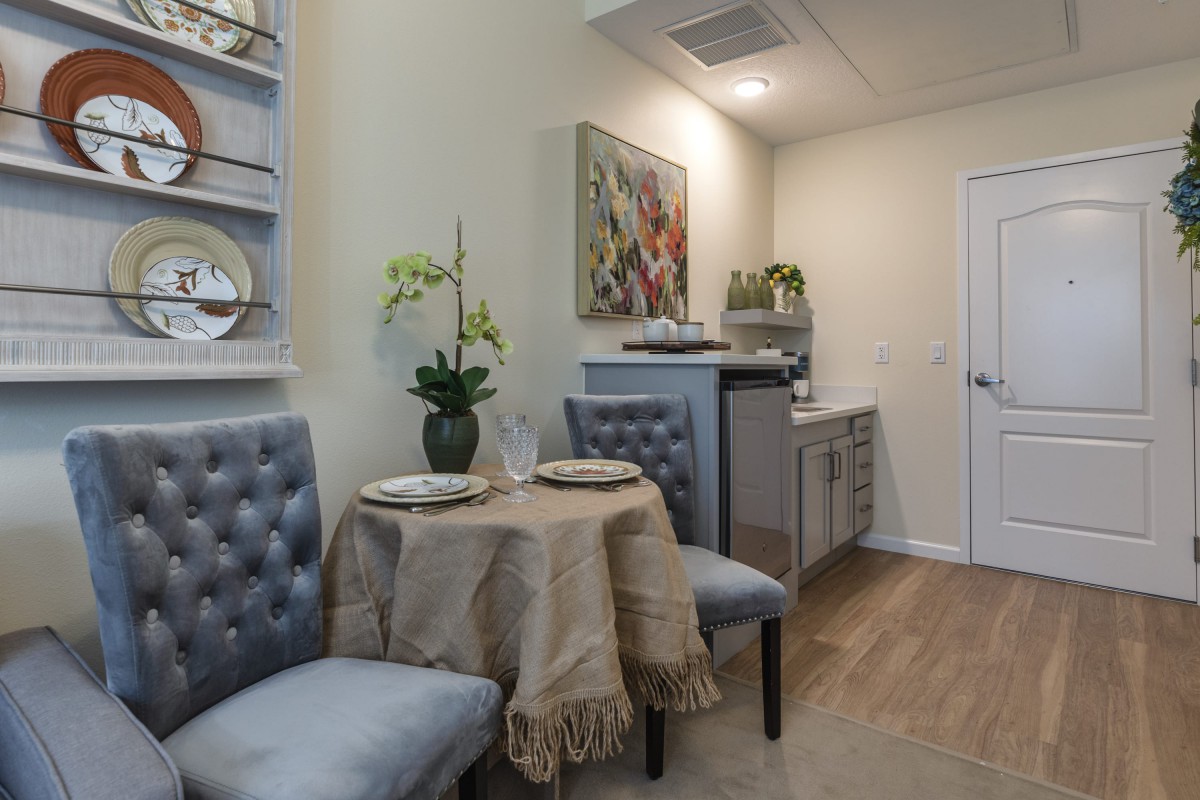 A cozy dining nook with a small round table, tufted chairs, and elegant decor.