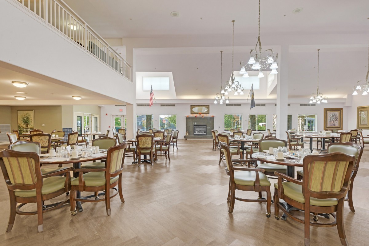 A spacious and elegant dining area with multiple tables and chairs arranged neatly, featuring stylish lighting fixtures.