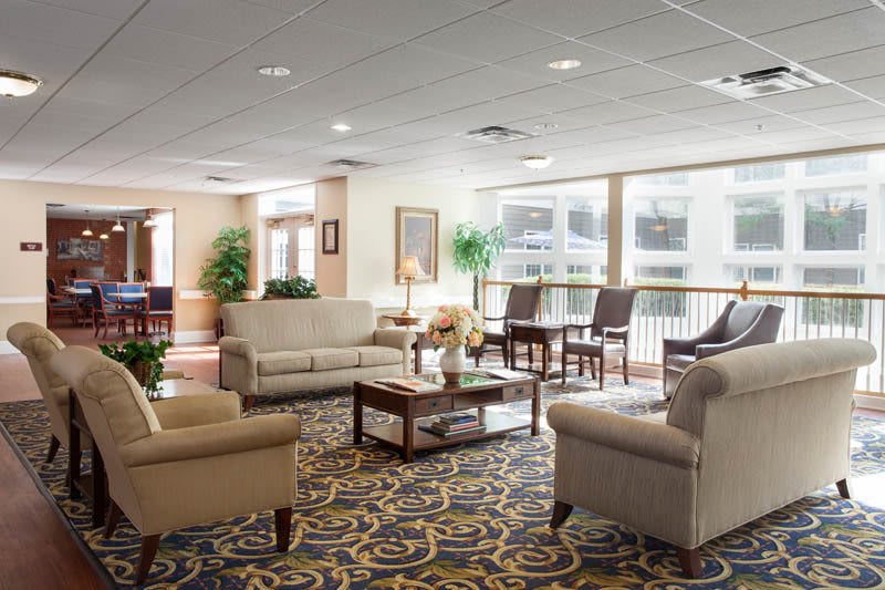 A cozy lobby area featuring comfortable sofas and chairs, a patterned carpet, and ample natural light.