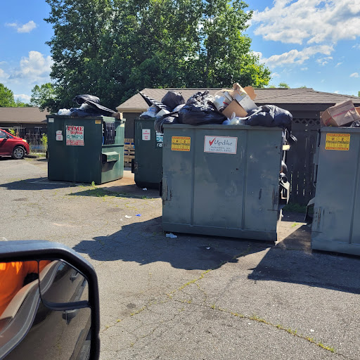 A row of dumpsters filled with garbage in a residential area.