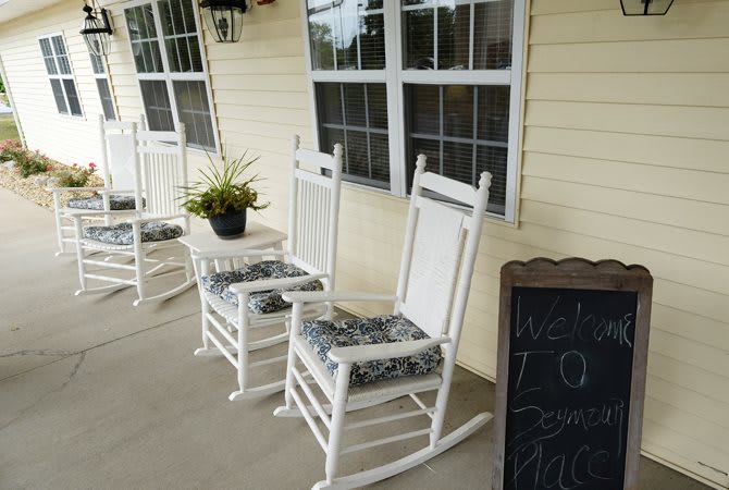 A cozy porch with white rocking chairs and a small table.