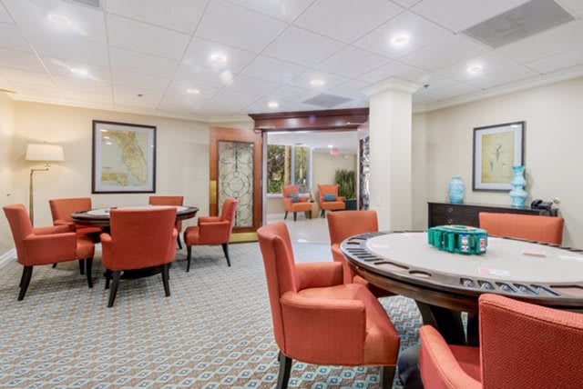 A comfortable lounge area with orange chairs and round tables, featuring maps on the walls.