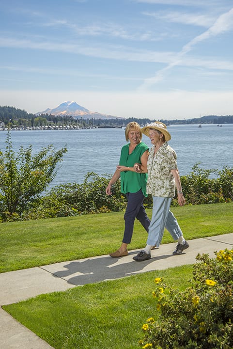 A couple enjoying a walk by the lake with scenic mountain views in the background.