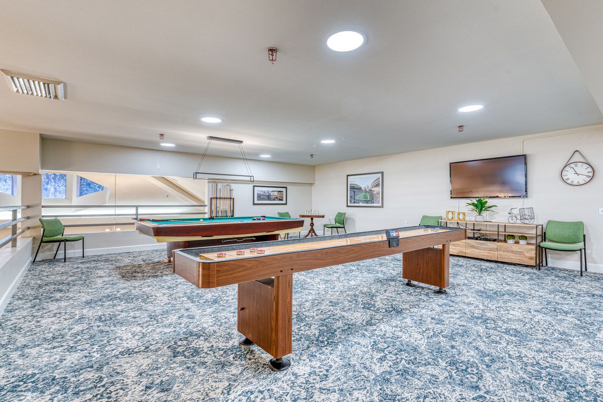 A spacious game room featuring a pool table and shuffleboard table, perfect for indoor recreation and leisure.