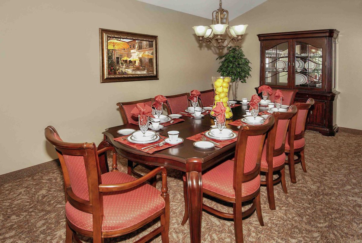 An elegantly set dining room table with matching chairs and a chandelier overhead.