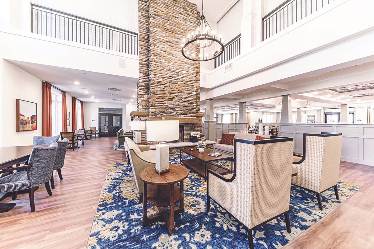 A modern lobby with a central stone fireplace and comfortable seating areas.
