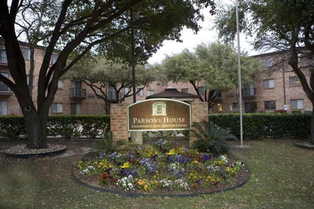 Entrance sign of a residential apartment complex surrounded by landscaping and trees.
