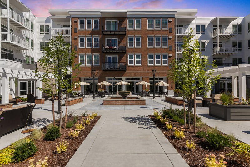 A modern apartment building with well-maintained landscaping and outdoor seating areas.