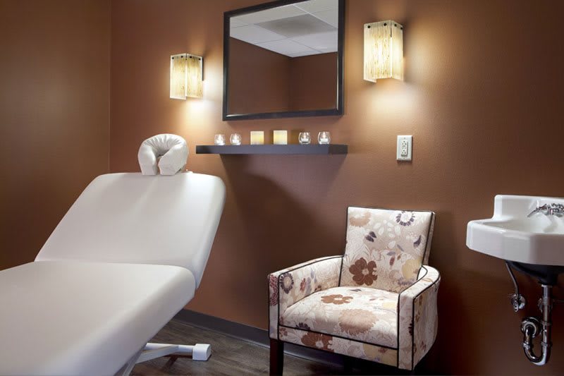 A serene massage room with a comfortable chair and calming candles.