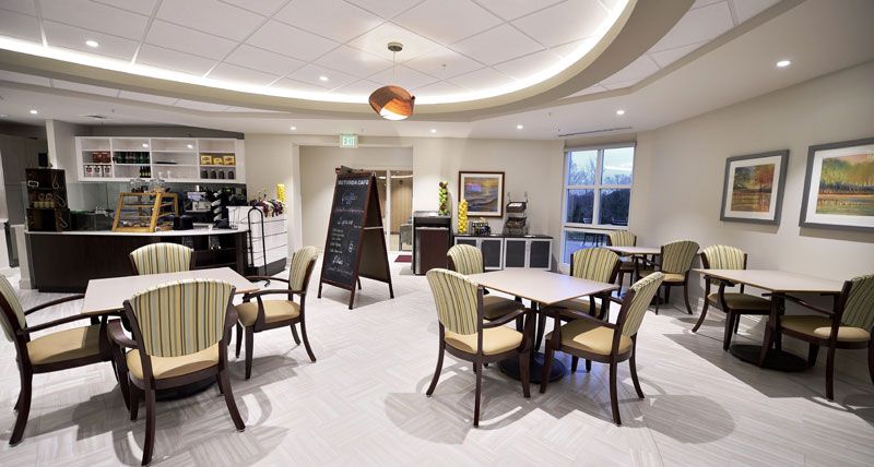 A modern cafe setting with tables, chairs, and a chalkboard menu.