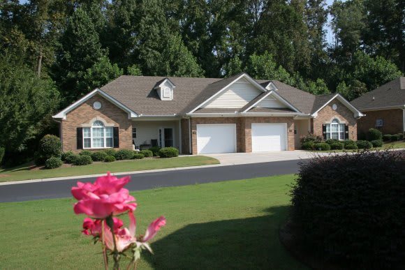 A suburban brick house with a well-maintained lawn and two garages.