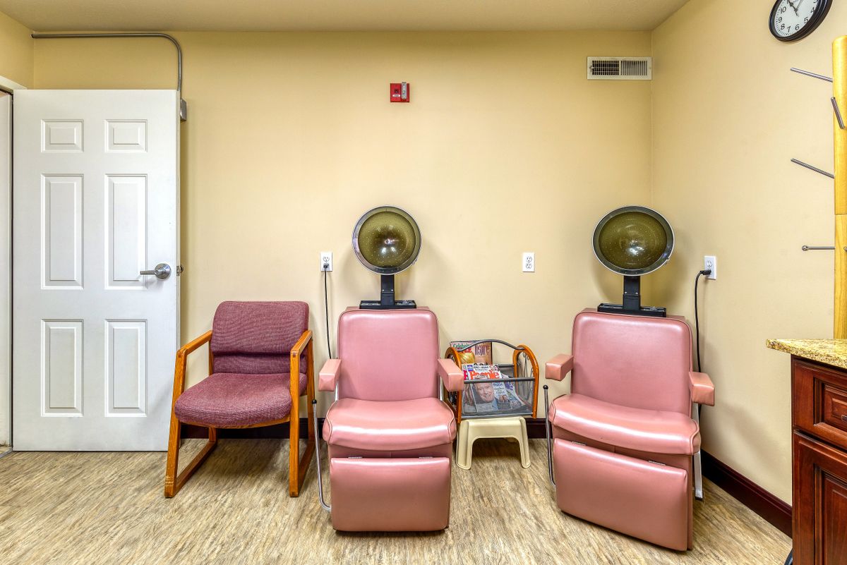 A cozy salon waiting area with vintage pink hair dryer chairs and seating.