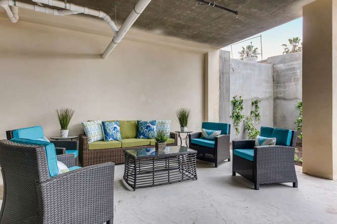 A modern outdoor patio with rattan furniture and colorful cushions.