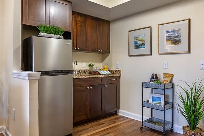 A cozy kitchen area in an apartment featuring wooden cabinets, a stainless steel refrigerator, and decorative artwork.