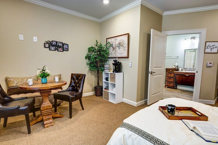 A cozy and well-decorated bedroom with a table, chairs, bed, and various decor items.