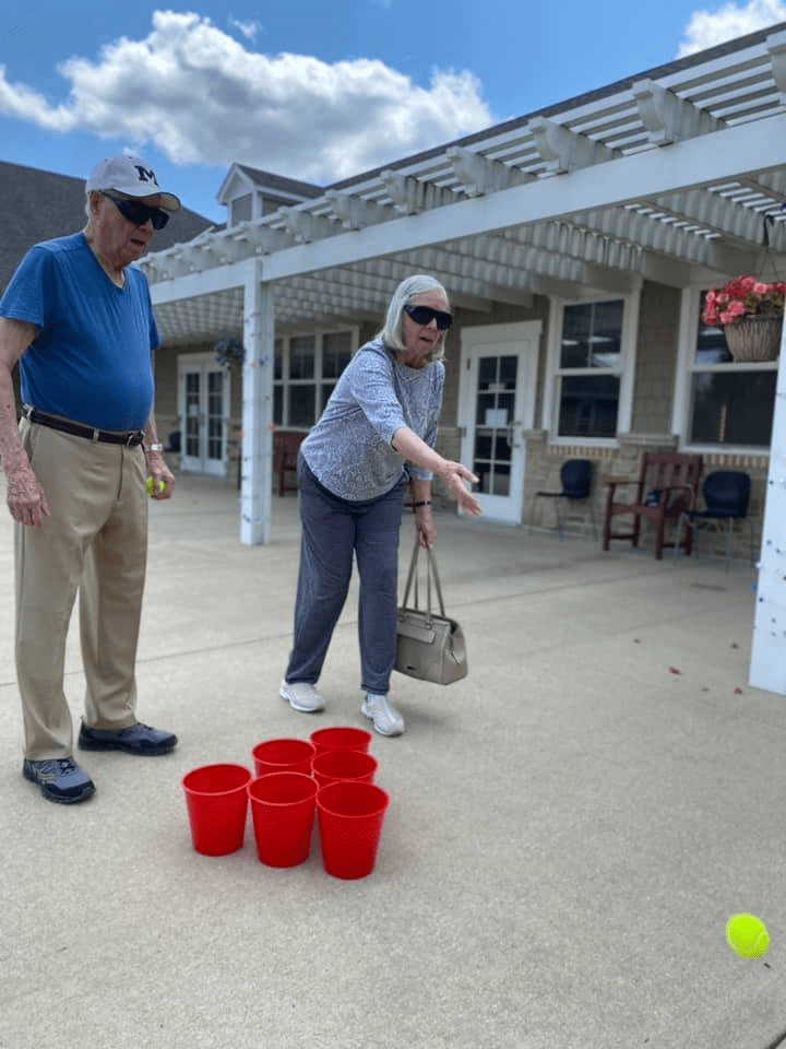 An elderly couple enjoying an outdoor game with red buckets.