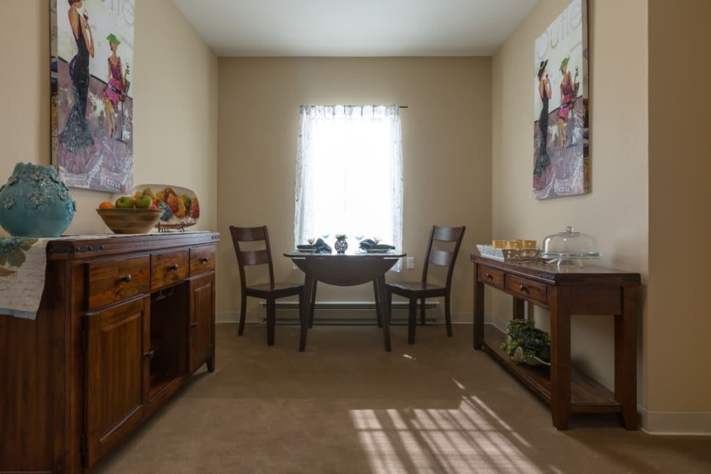 A cozy dining room with a small table and two chairs, decorated with artwork on the walls.