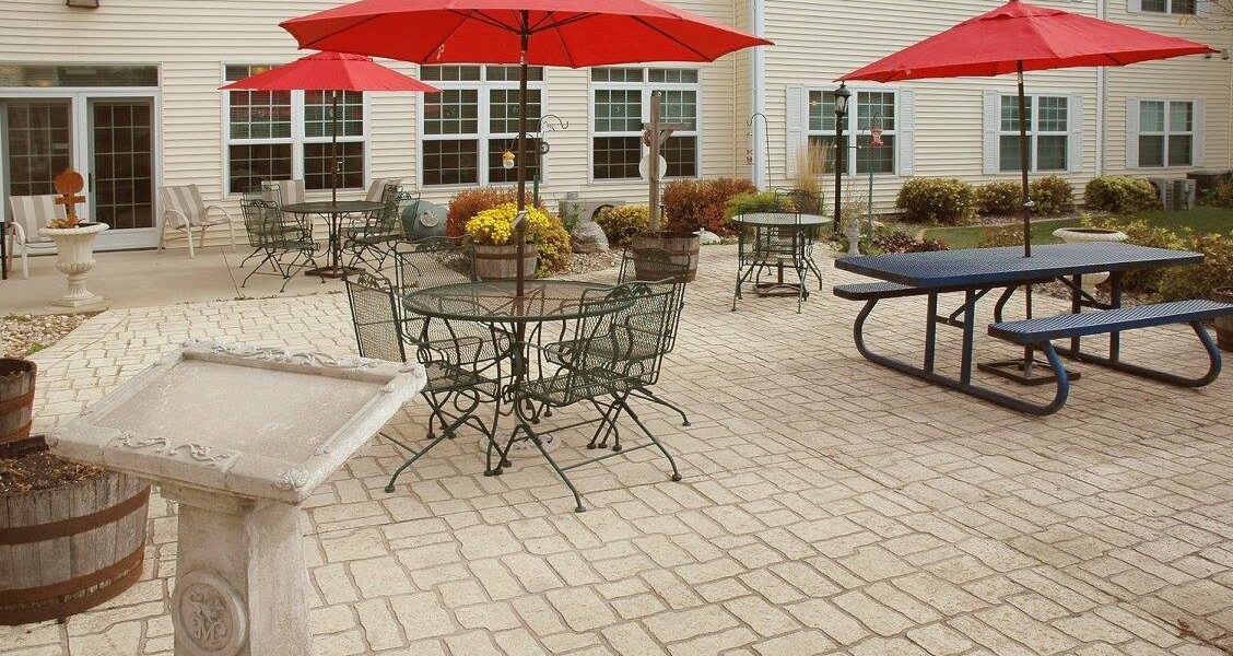 An outdoor patio area with tables and chairs under red umbrellas.