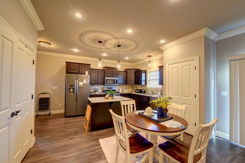A modern kitchen with wooden flooring, pendant lighting, and a dining area.