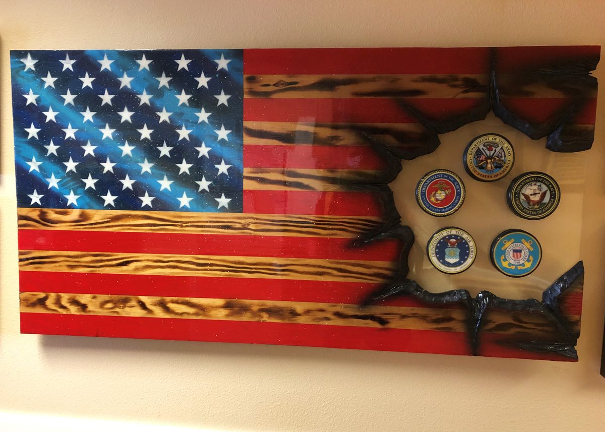 A wooden American flag with military emblems inset as decorative wall art.