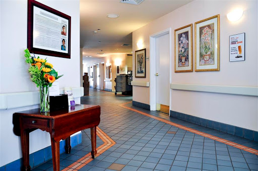 A well-lit hospital hallway featuring artwork, a flower arrangement, and inviting decor.