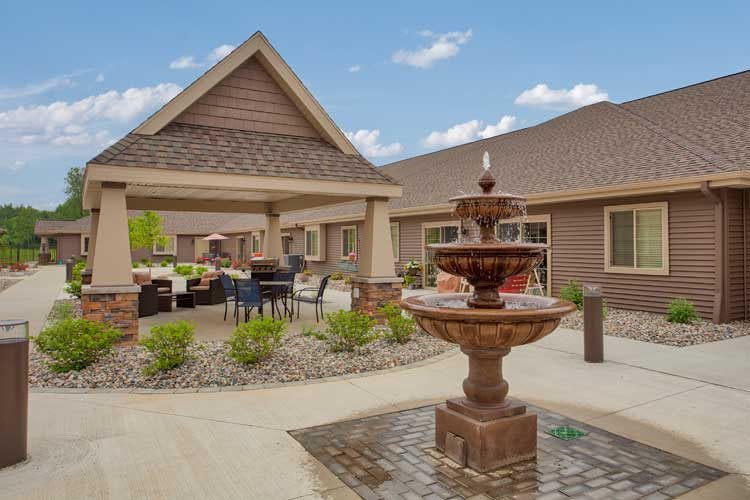 A serene outdoor area featuring a fountain and covered patio with seating.