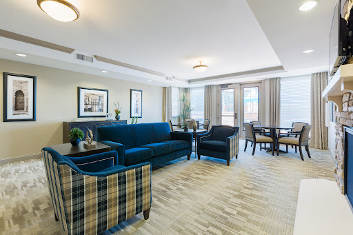 A modern and inviting living room area featuring a blue sofa, plaid chairs, and ample natural light.