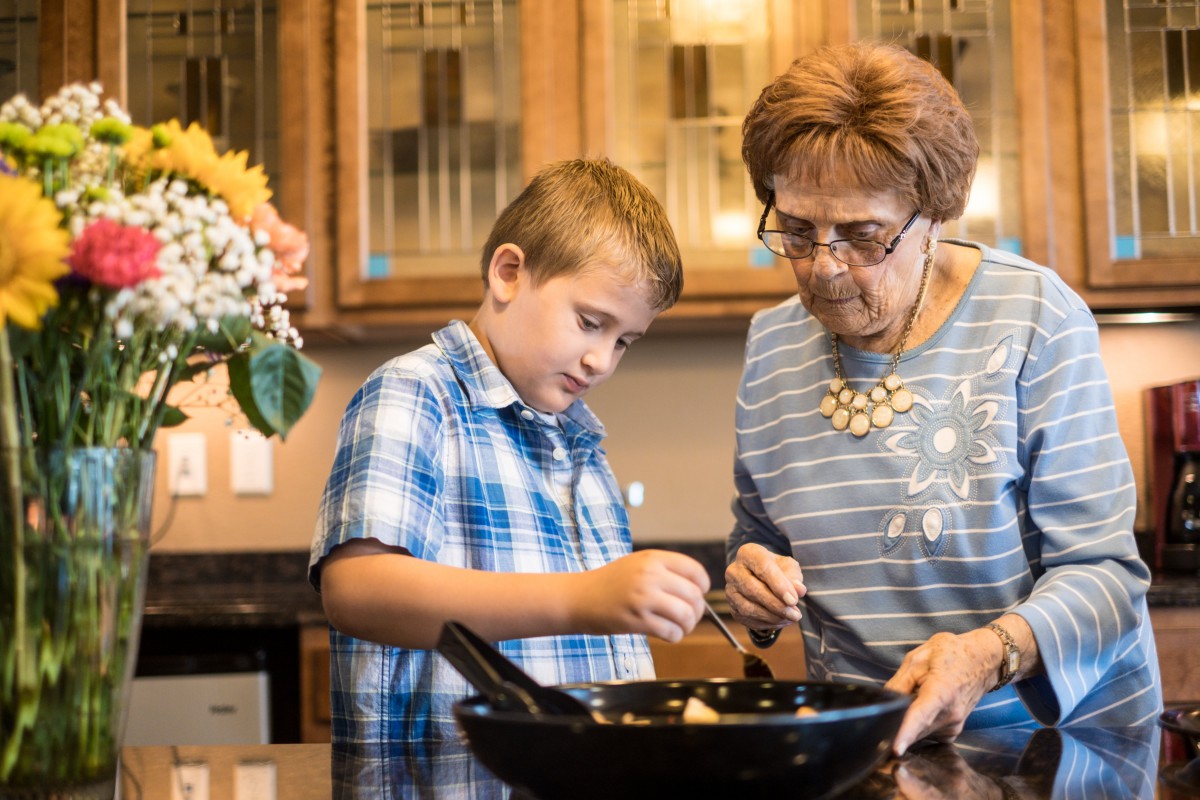 A boy and an elderly woman cooking together in the kitchen.