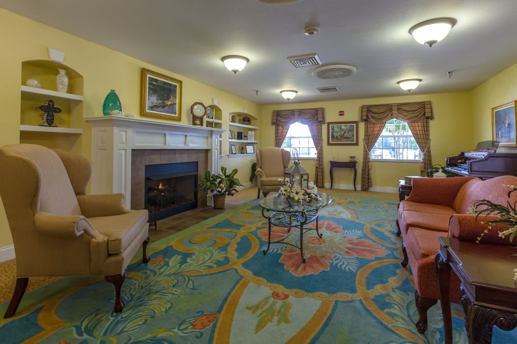 A cozy living room with a colorful carpet and comfortable seating arrangement around a fireplace.