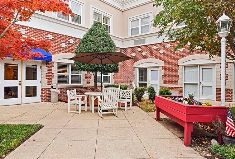 Cozy outdoor patio area with seating and greenery outside a brick building.