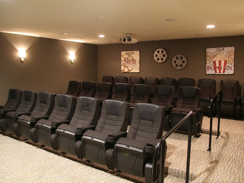 A cozy home theater setup with multiple rows of comfortable seating and a projector.