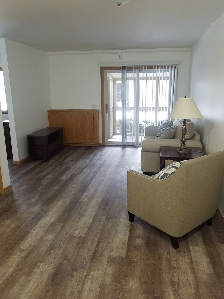 A minimalist living room with hardwood floors and simple furnishings.