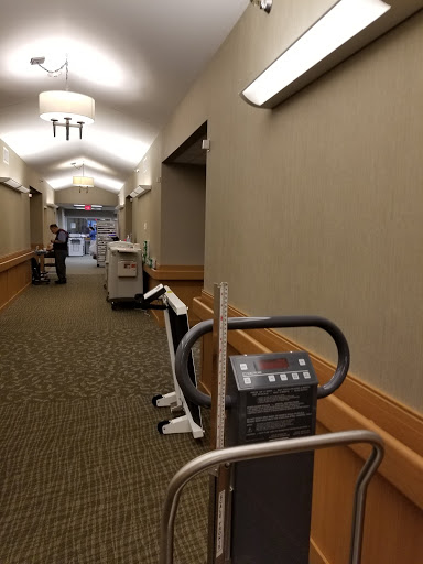 A view of a well-lit hallway featuring exercise equipment and carpet flooring.