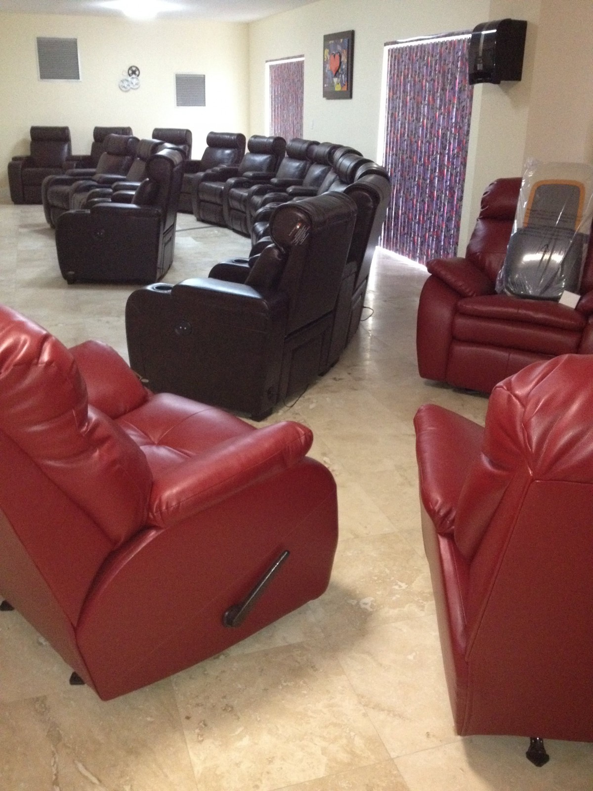 A spacious living area featuring a collection of red and black recliner chairs arranged in a circular formation.