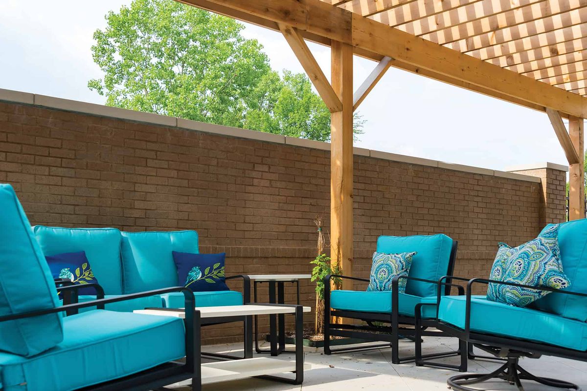 A cozy patio setup featuring blue-cushioned furniture under a wooden pergola.