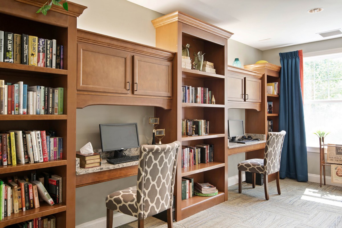 A well-organized home office with wooden desks and bookshelves.