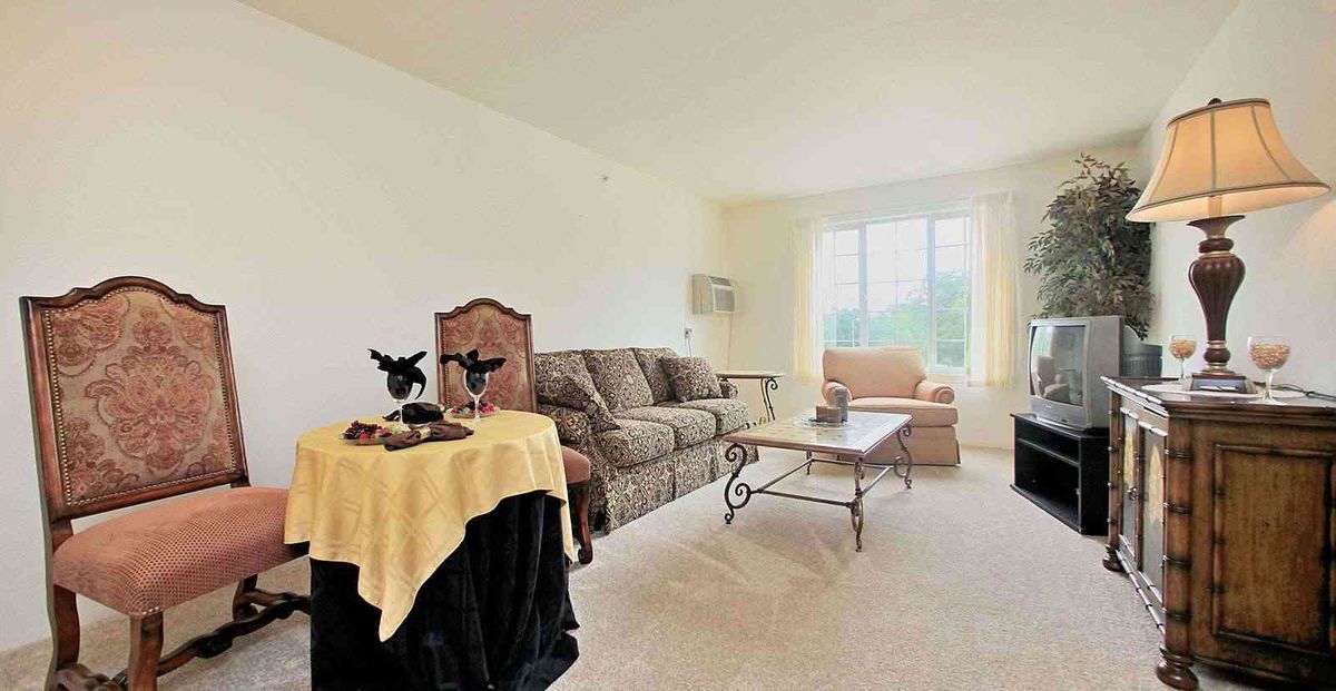 A cozy living room with a sofa, chair, and coffee table near a large window.