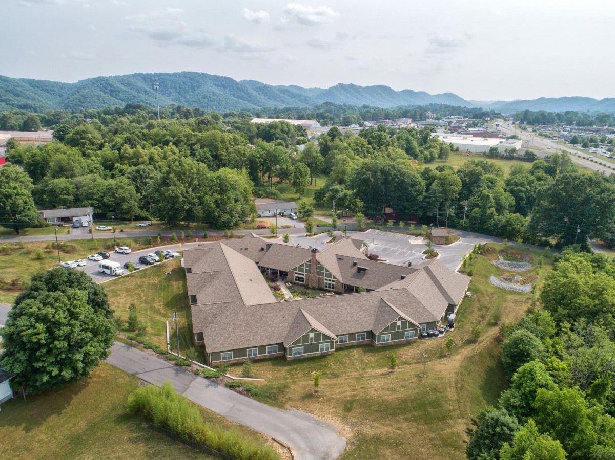 Aerial view of a large building surrounded by lush greenery and mountains.