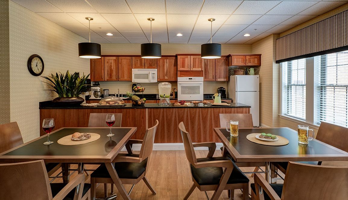 A modern kitchen with wooden cabinets, dining tables and chairs, and various appliances.