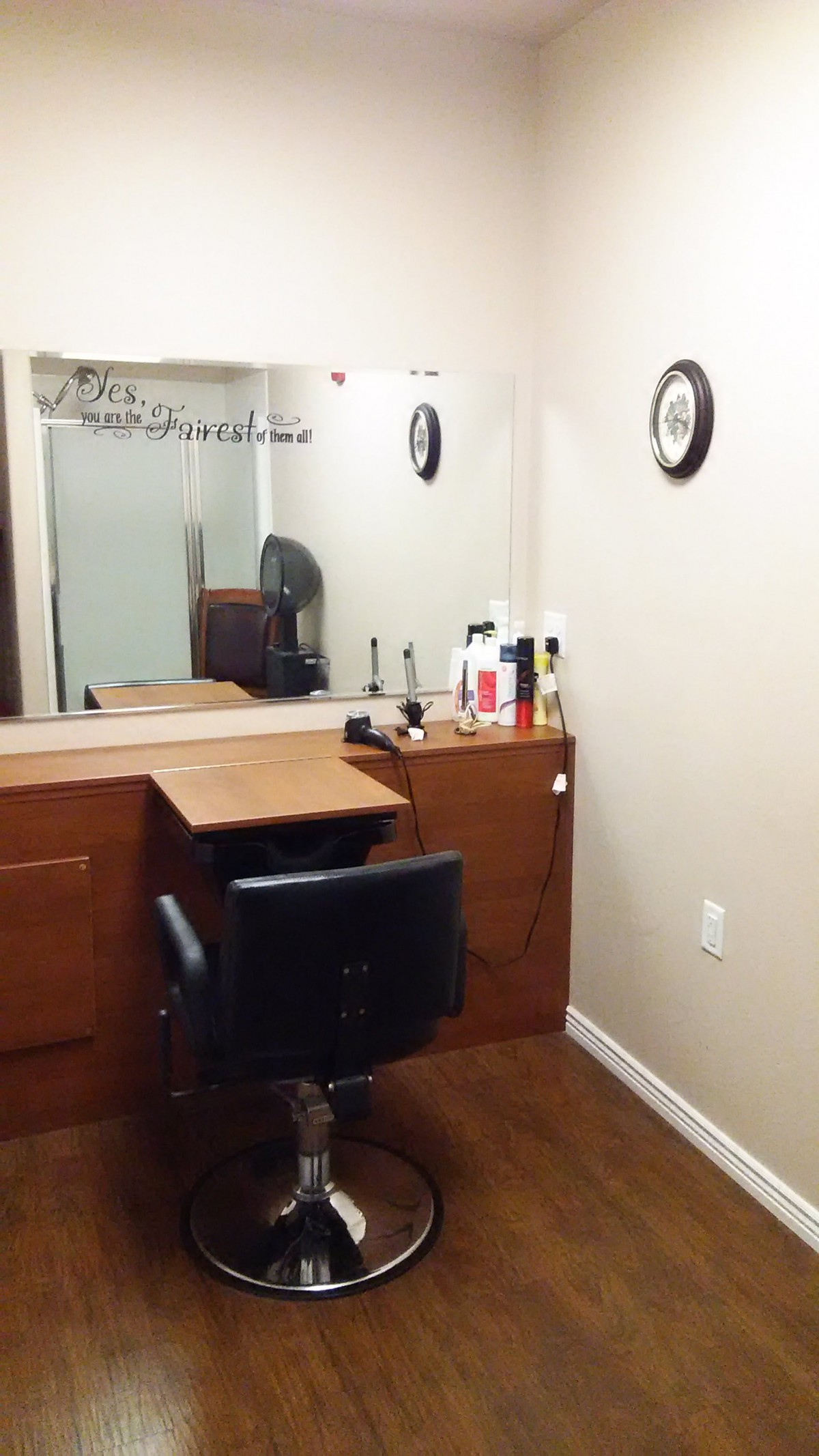 A cozy hair salon with a styling chair, mirror, and various hair products on a wooden counter.