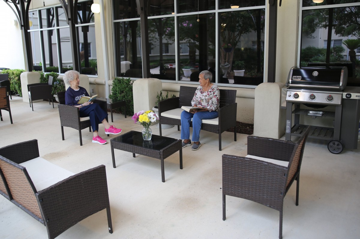 Two elderly people sitting on a patio, enjoying a leisurely reading session.
